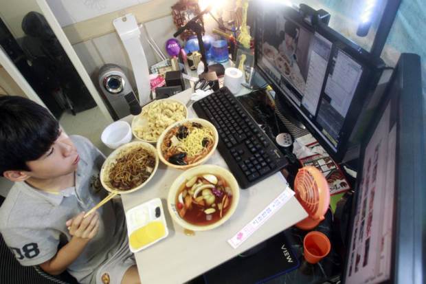 rapaz a comer em frente ao pc a ver vídeo sobre como limpar teclado